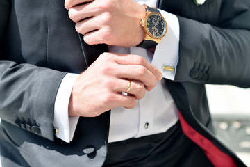 Groom is wearing cuff-links indoors