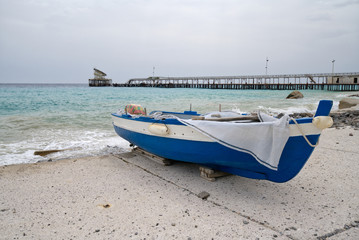 Disembarked blue boat in front of an abandoned shipping pier