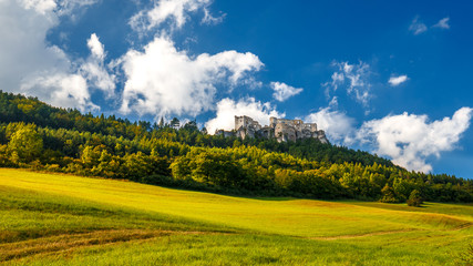 The ruins of a medieval castle Lietava on a rocky blade over a wooded landscape and grassy meadows, nearby Zilina town, Slovakia, Europe.