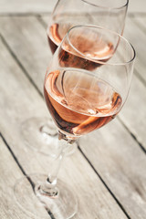 Two glasses of rose wine on wooden table, shallow DOF