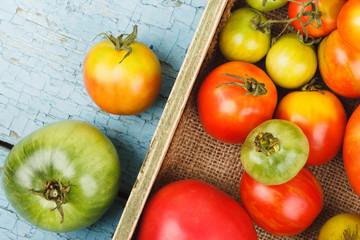 Set of different sorts of ripe tomatoes in the wooden tray