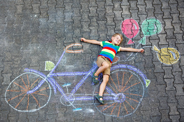 little kid boy having fun with bicycle chalks picture on ground