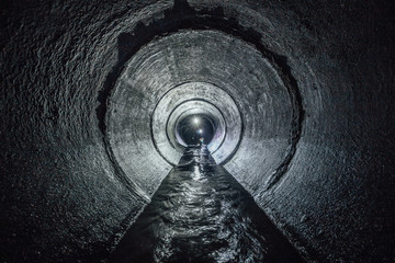 Diggers are exploring underground river flowing in round sewer tunnel - obrazy, fototapety, plakaty