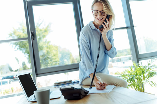 Pleasant Woman Talking On Phone And Putting Down Information