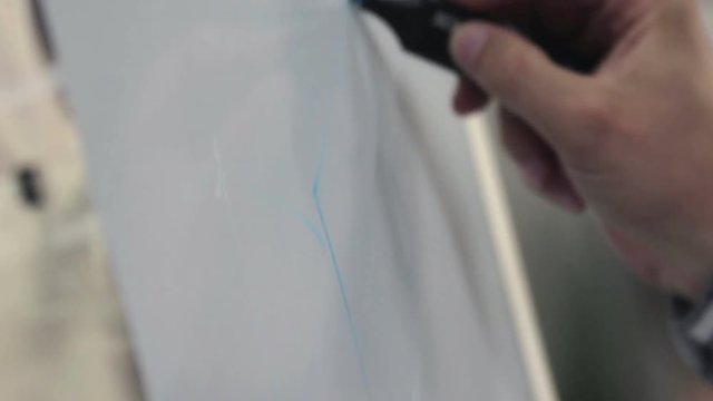 Desiner draws a sketch close-up on a flipchart with a blue marker