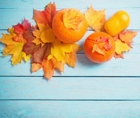 Fototapeta na wymiar autumn leaves and pumpkins on blue wooden background