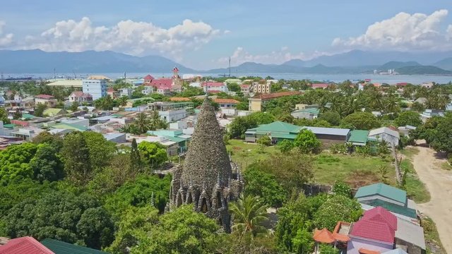Coral Buddhist Temple in City against Sea Hills and Blue Sky