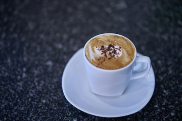 Hot Coffee in white glass on the floor of black marble.