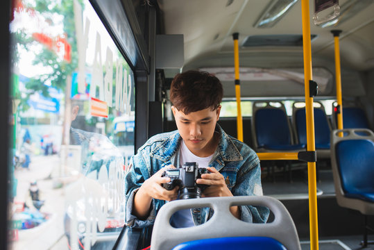Asian male tourist photographing the city from the window of the bus