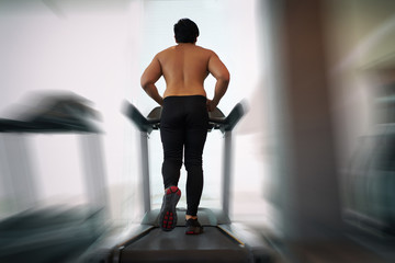 Obraz premium Asian men do not wear shirts, running on a treadmill in the gym.