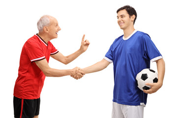 Old soccer player shaking hands with young player