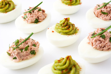 Variety of stuffed eggs with avocado and tuna isolated on white background

