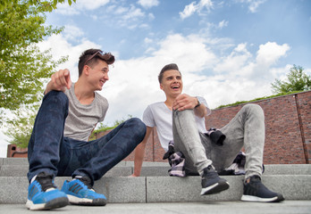 Two friends sitting on stairs in town and laughing, best friend concept