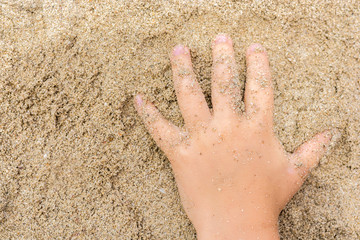 Kind spielt beim Badeurlaub im Sand
