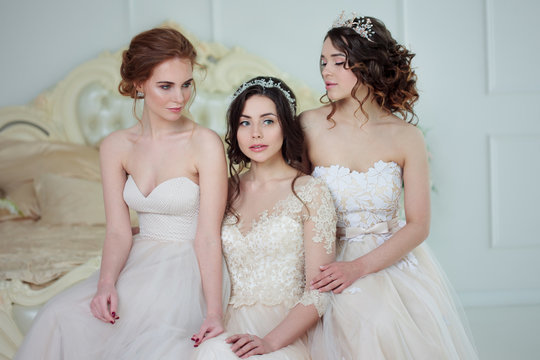 Three girls in wedding dresses. Beautiful delicate girls in the Bridal salon