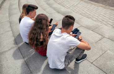 Group of friends sitting together using their phones