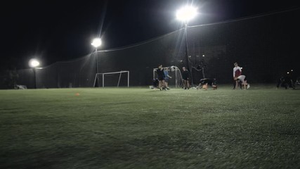 Soccer football players during the team training before the match. Exercises for football soccer youth team. Young player exercises with ball and marker cones, running training rugby men athlete