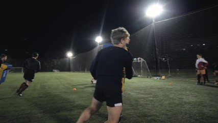 Soccer football players during the team training before the match. Exercises for football soccer youth team. Young player exercises with ball and marker cones, running training rugby men athlete
