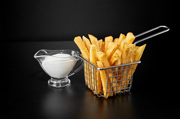 French fries in basket with sauce isolated on black background. Above view.