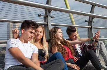 Group of friends sitting together outdoor on urban scenery