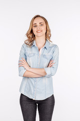 Young woman in  jeans shirt  with crossed arms smiling and looking at camera isolated on white...