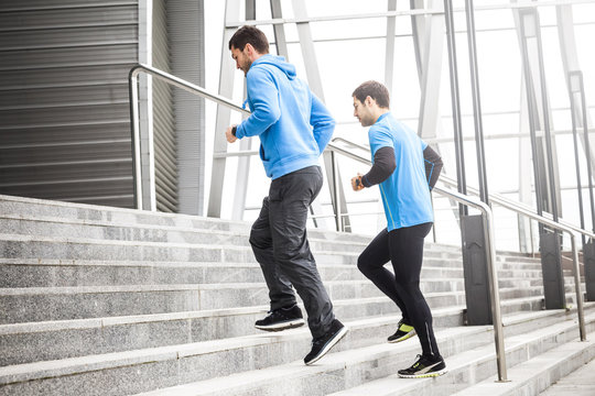 Two male runners warming up on staircase