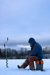 elderly man fishing in the winter on the lake