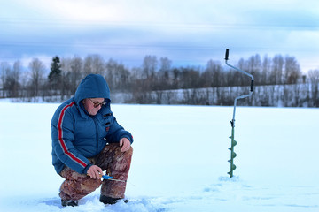 Fototapeta na wymiar elderly man fishing in the winter on the lake