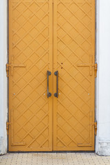 Antique looking yellow metal door with iron handles