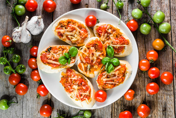 Italian bruschetta with tomatoes and basil, spicy appetizers, top view on plate for party or sharing with friends