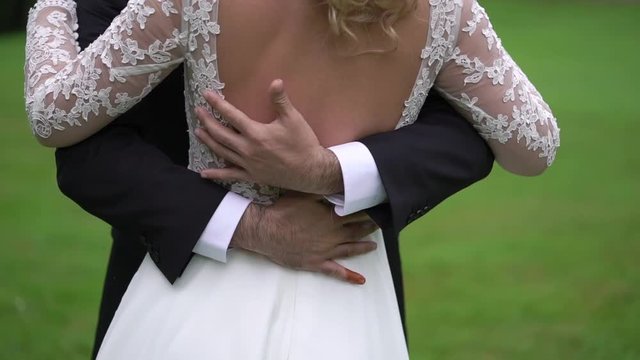 Unrecognizable bride and groom hugging in a park