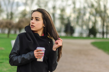 Girl beautiful young brunette with long hair . Morning in the Park drinking coffee and playing sports