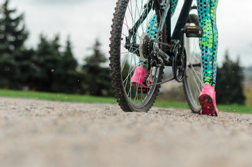 the girl the brunette in sportswear, rides a bike in the morning in the park. Close up a leg,
