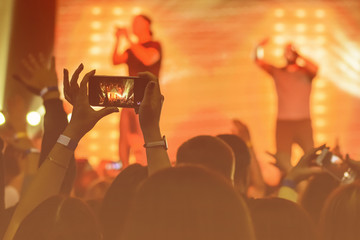 silhouette of hands with a smartphone at a concert