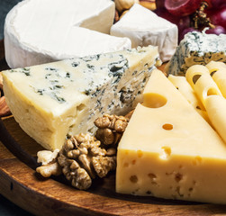 assorted cheeses with mold, Maasdam, Roquefort, brie and others on a wooden table