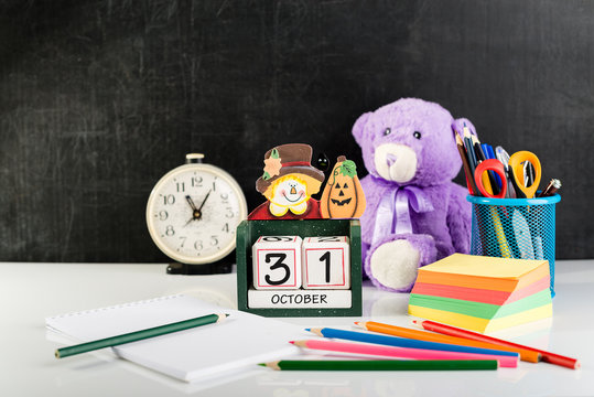All Saints Day Concept and Samhain, traditional American holiday, Halloween. Cube shape calendar for October 31, open notebook, scissors, stickers, pencils and teddy bear on light table. - Powered by Adobe