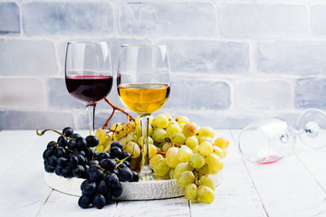 Red and white wine in glasses with grapes on white background. Assortment of autumn harvest beverages. Copy space