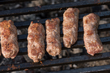 Flat lay above minced meat kebabs frying on the barbecue grill