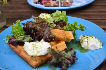 serving salad at a restaurant or cafe for tourists. Beautiful salad in a blue plate with cheese and leaves