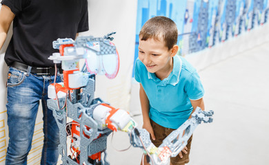 a little boy is talking and in touch with an anthropoid robot