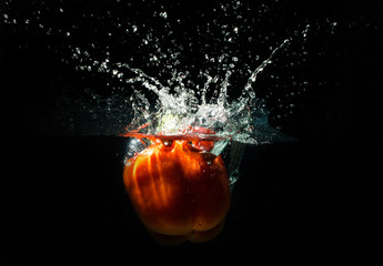 Red pepper splashing water on black background
