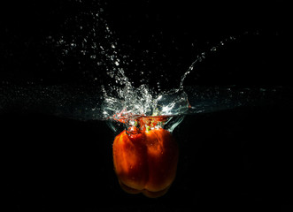 Red pepper splashing water on black background