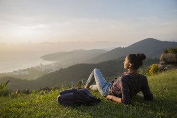 Hipster young girl with backpack enjoying sunset on peak mountain. Tourist traveler on background valley landscape view mockup.