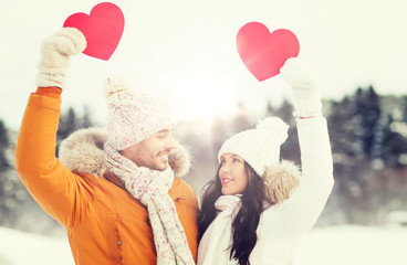 happy couple with red hearts over winter landscape