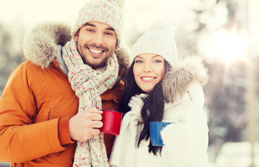 happy couple with tea cups over winter landscape