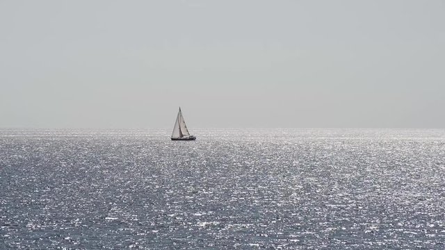 barca a vela solca il mare in controluce