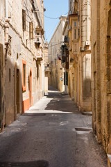 Fototapeta na wymiar Narrow medieval street with stone houses in Mdina, Malta