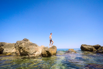 teenager standing on the rocks at seaside - summertime - Sicily mediterranean sea
