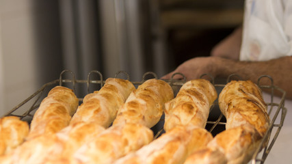 Homem retirando fornada de pãp francês fresco do forno em padaria no brasil foco seletivo