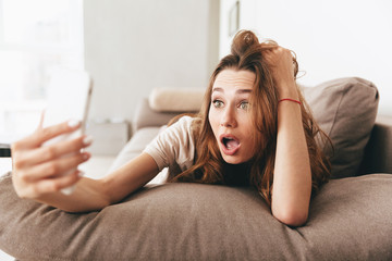 Shocked emotional pretty lady make selfie by phone.